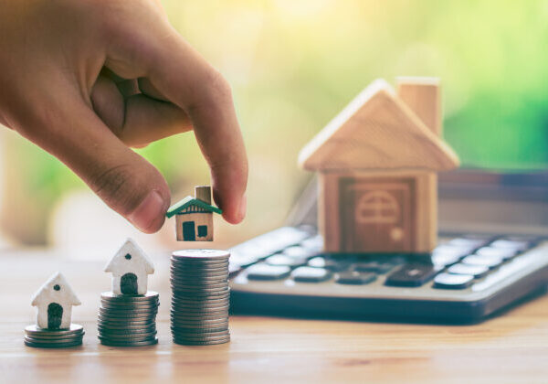 House On Coins And House Put On Calculator. Man's Hand Putting H House On Coins And House Put On Calculator. Man's Hand Putting H